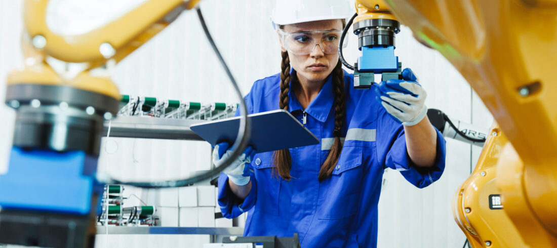 Engineer reviewing production data on a tablet beside an automated manufacturing line