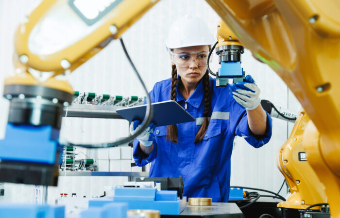 Engineer reviewing production data on a tablet beside an automated manufacturing line